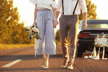 Fototapeta premium Happy wedding couple and decorated car, outdoors