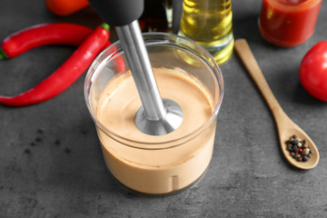 Blending creamy tomato sauce for fish taco in bowl on kitchen table