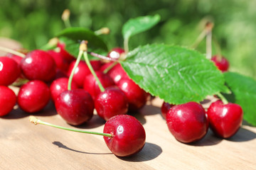 Tasty ripe cherries on wooden board outdoors
