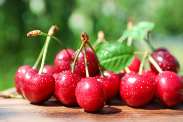 Tasty ripe cherries on wooden table outdoors