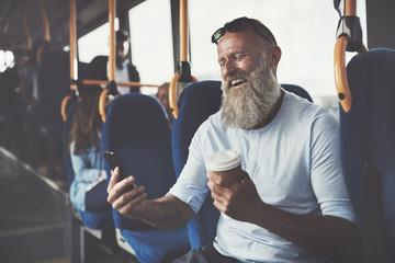 Mature man laughing at a text while riding the bus