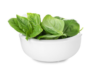 Green fresh organic basil leaves in ceramic bowl isolated on white