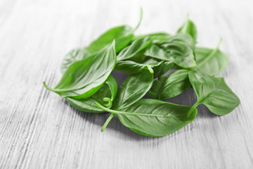 Pile of green fresh organic basil leaves on wooden background