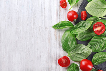 Cherry tomatoes and green fresh organic basil on wooden background