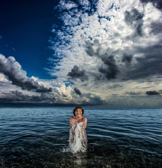 Woman in the sea playing with water against the sky