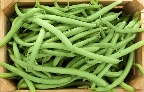 Raw fresh organic green beans in wooden crate, close up