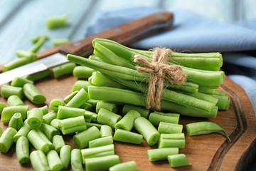 Wooden board with fresh green beans on table, close up