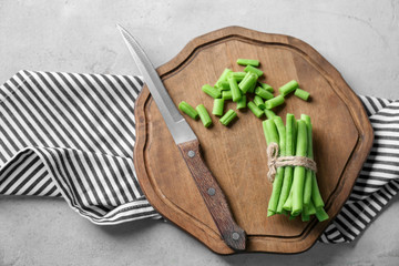 Wooden board with fresh green beans on table