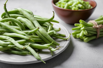 Plate with fresh green beans on table