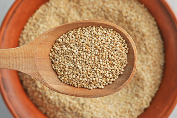 White quinoa in wooden spoon on blurred background, closeup