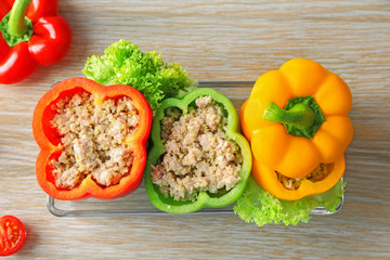 Quinoa stuffed peppers in baking dish on wooden background