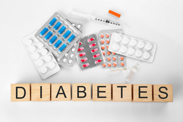 Composition with medicaments and word Diabetes made of wooden cubes on light background