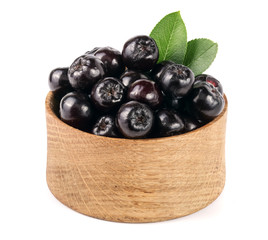 Chokeberry with leaf in wooden bowl isolated on white background. Black aronia berries