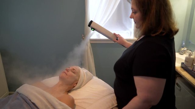 Massage receives a steam treatment on her face during her facial. Steadicam shot.