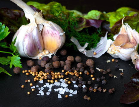 Garlic, pepper, salt and herbs on a dark black