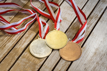 Gold, silver and bronze medals at wooden texture table with white and red ribbon - 171903755