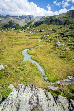 vue verticale sur un ruisseau de montagne avec un rocher en premier plan et des montagnes en arrière plan