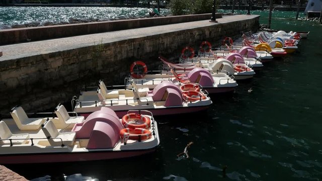 Catamarans sway on the waves at the pier on Lake Garda on a sunny day