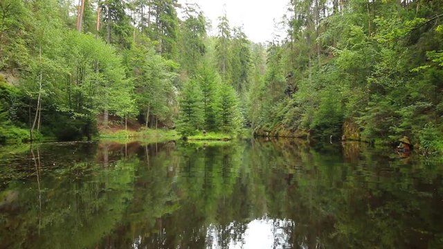 Reflection of forest in small lake in the rock mountain Adrspasske skaly in Czech republic