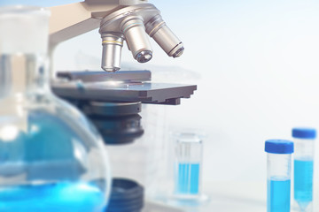 Scientific background with closeup on light microscope and blurred laboratory