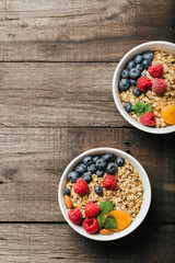 Homemade granola with dried fruit and berries on wooden background
