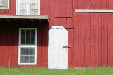Red painted barn with white door and window trim 
