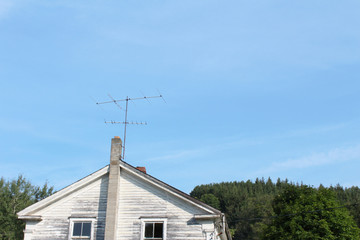 Vintage television antenna attached to a cinder block chimney on an old house
