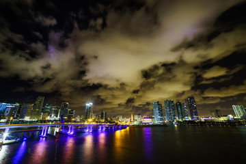 Fototapeta premium Miami city skyline panorama at dusk with urban skyscrapers and bridge over sea with reflection