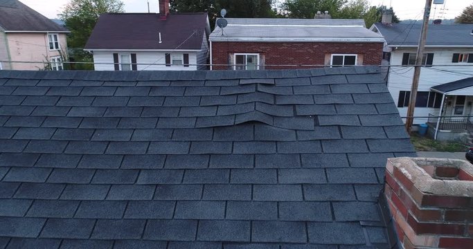 A simulated video feed of a roof inspector's unmanned drone examining a home's damaged shingled roof after a storm.  	