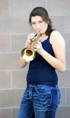 Female jazz trumpet player blowing her horn outside.