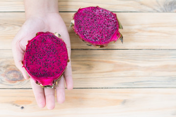 Red  dragon fruit in hand on wooden background