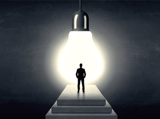 Man standing on a step in front of a huge light bulb