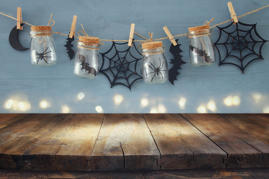 Halloween Holiday Concept. Empty Old Wooden Table In Front Of Masson Jars With Spiders And Baths Decorations