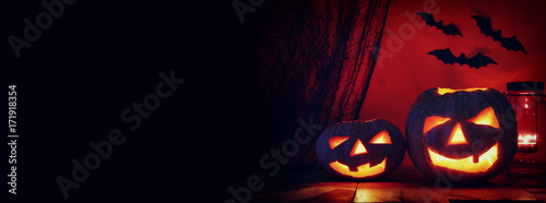 Halloween Pumpkin on wooden table in front of spooky dark background. Jack o lantern