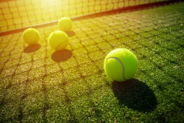 Fototapeten Tennis balls on grass court with sunlight © kireewongfoto