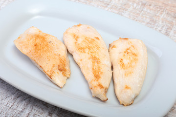 Slices of roasted chicken breast and tomato on white plate