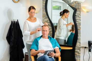 Fototapeta premium female hairdresser cutting hair of man