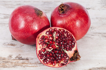  Fruit of red pomegranate on wooden plank, half with seeds,  close up