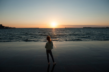 Fototapeta na wymiar lonely little girl looking at the sea sunset