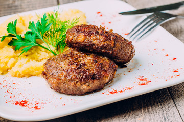 Mashed potatoes and cutlet on white plate on wooden table