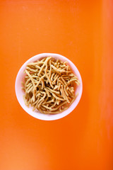 Fototapeta na wymiar Traditional Indian Snacks on white bowl on orange background
