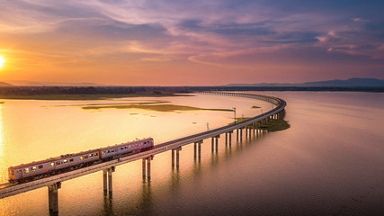 Aerial View The train is running on the bridge Over River Pa Sak Dam Lopburi Thailand and Beautiful sunset - Powered by Adobe