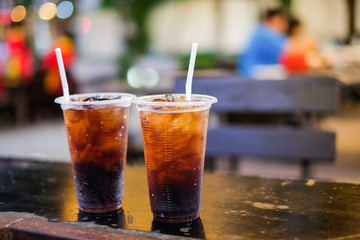 Soft drink with ice and white tube in plastic glass set on the table for background or texture - relax concept.