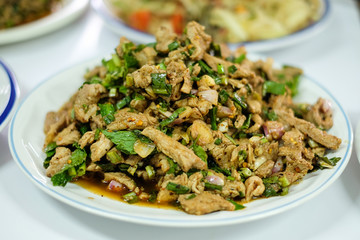 Homemade hot and spicy sliced grilled pork salad (Nam Tok Moo) serve on white plate for food background or texture - Thailand.