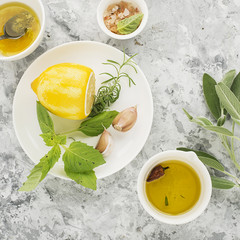 Ingredients for homemade lemon sauce vinaigrette dressing for salad with olive oil, salt, pepper, lemon, lemon zest, juice, garlic and herbs to taste. Top view on a light background.