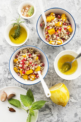 A healthy modern snack or lunch. Two bowls with pearl barley salad with slices of baked pumpkin and pomegranate seeds with butter dressing sauce. Top View.