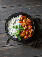 Rice with braised lima beans in tomato sauce on a dark background, top view. Vegetarian food concept