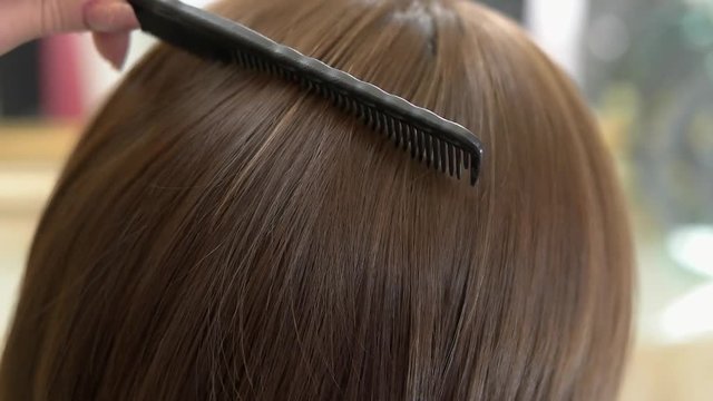 Comb brushing female hair. Brown hair close up.