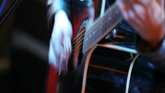 Woman's hands playing acoustic guitar on concert
