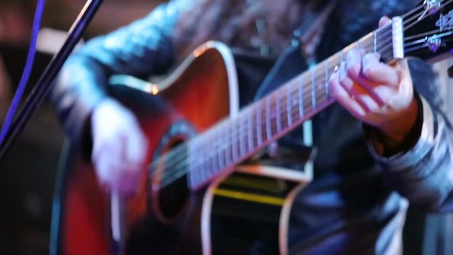 Woman's hands playing acoustic guitar on concert